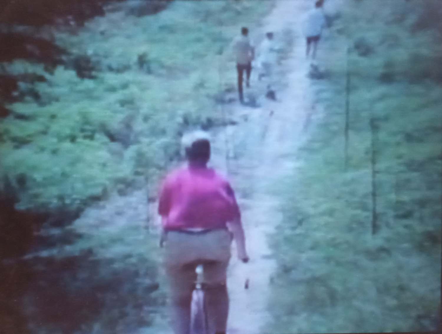 In 8mm footage, a cyclist follows runners on a dirt trail of Buffalo Bayou in June 1968
